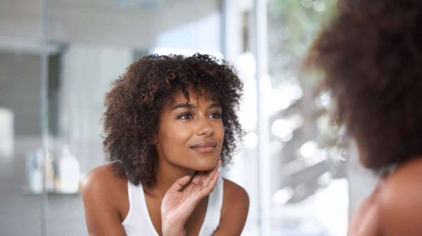 Woman with curly brown hair looking at herself in the mirror