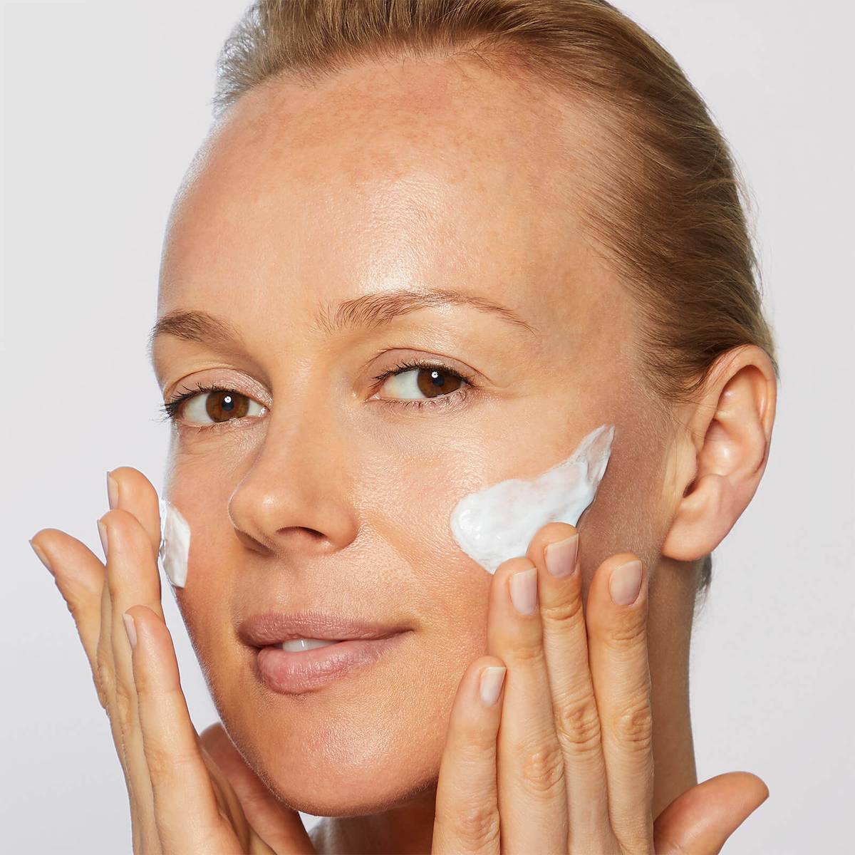 Woman applying No7 Laboratories skincare products to her face