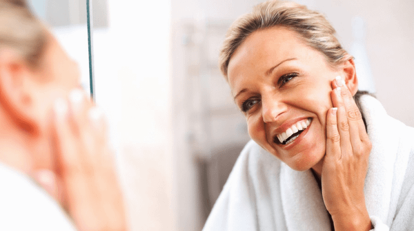 Woman smiling at herself in the mirror checking her face