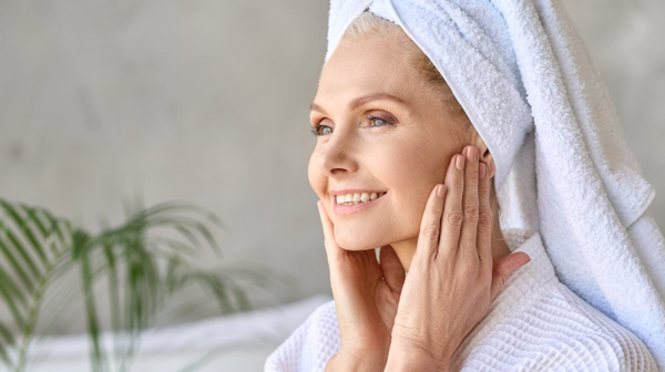 Woman with a towel on her head smiling and touching her face
